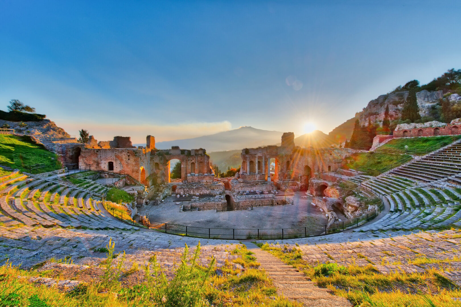 Ancient theatre of Taormina Siciliy Italy  with Etna erupting volcano at sunset
