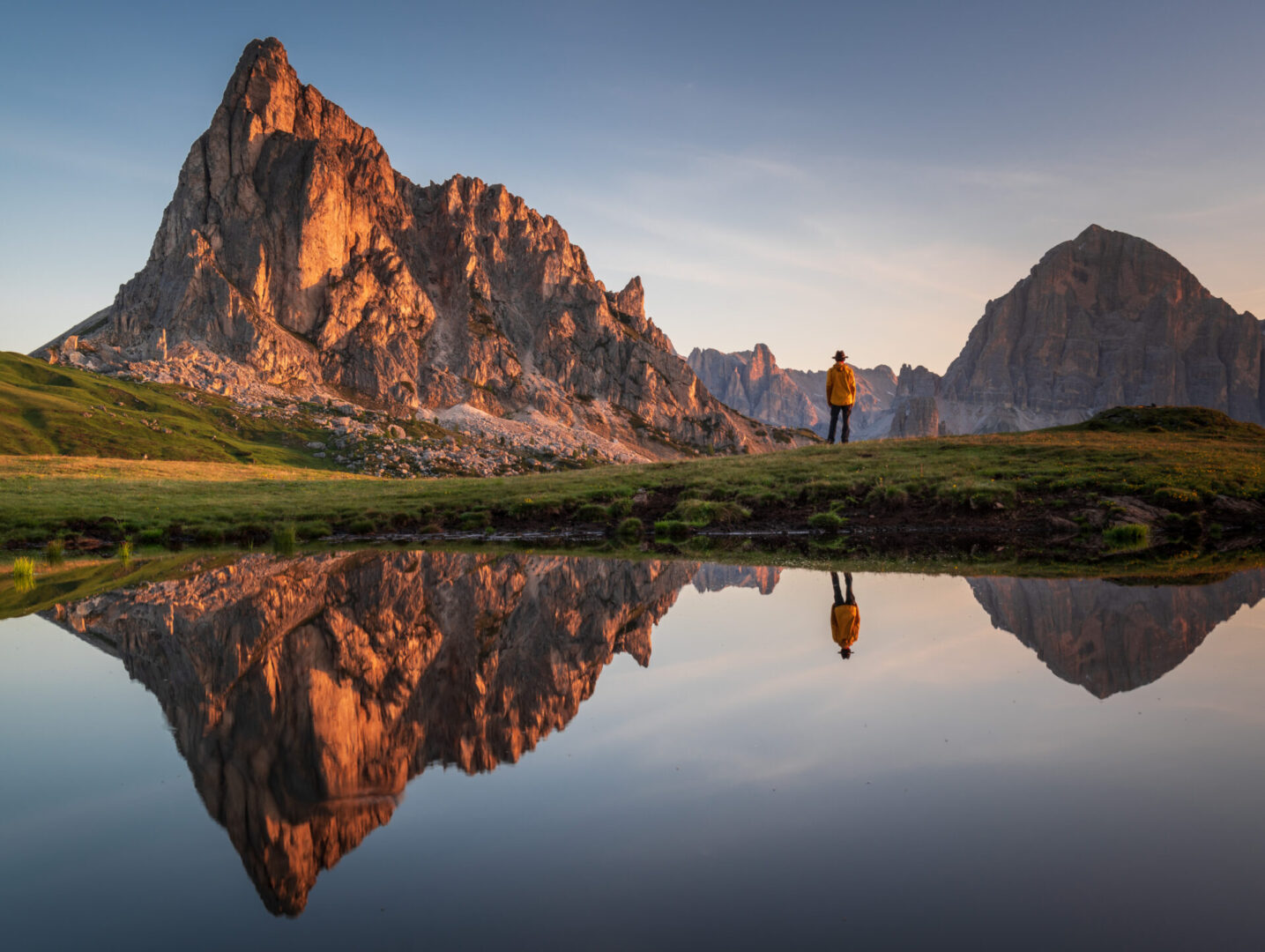 Reflection in the water of a man in the distance looking at the mountains at sunrise Reflection in the water of a man in the distance looking at the mountains at sunrise