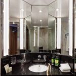 Modern bathroom sink area with large mirrors and ambient lighting.