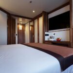 Modern hotel room with cozy bed and sleek wooden accents.