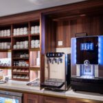 Modern coffee machine and syrup bottles on a wooden counter.