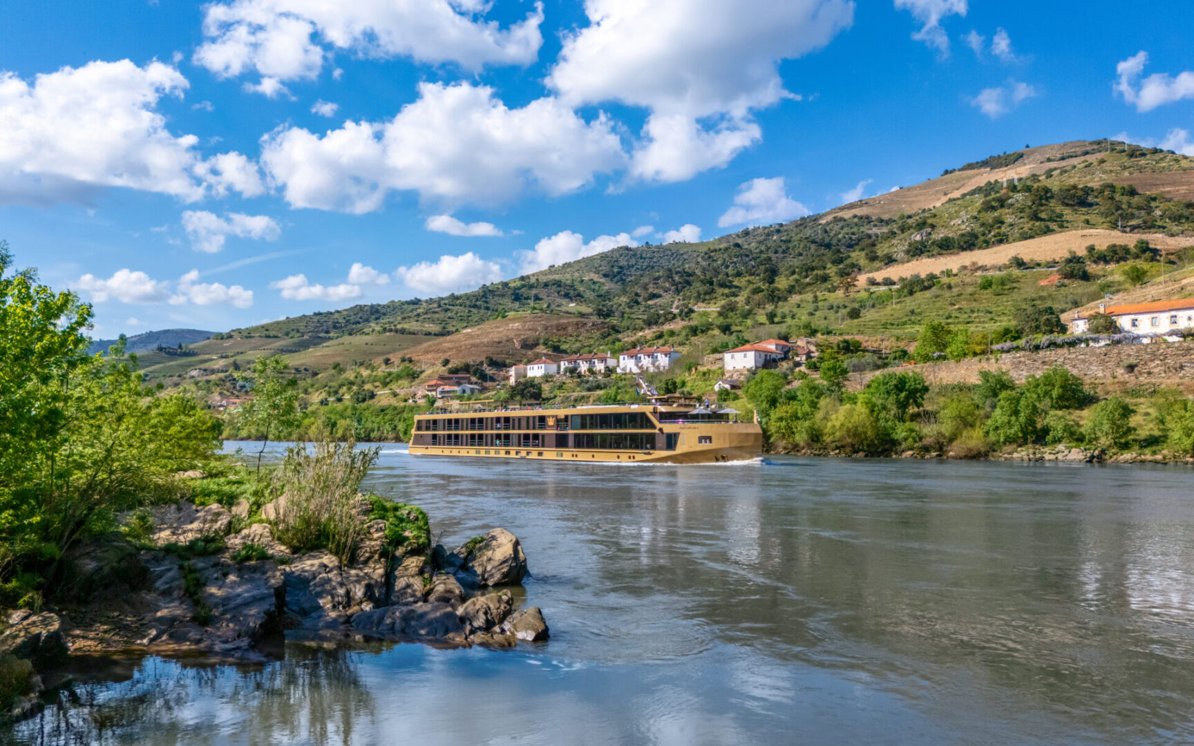 Scenic riverside with hills under a blue sky.