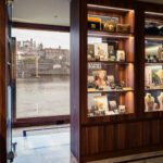 Cozy bookstore interior overlooking a river through large windows.