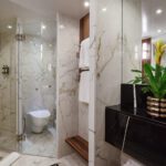 Modern bathroom with glass shower and marble walls.