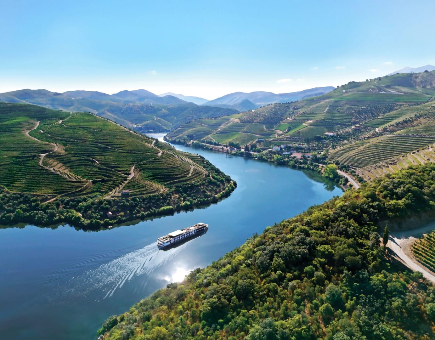A river winding through green hills with a boat cruising.