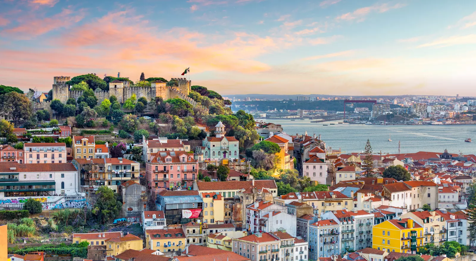 Colorful hillside town overlooking a large body of water at sunset.