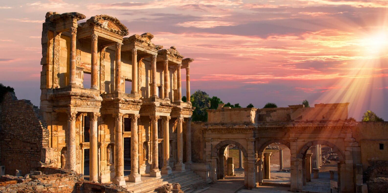 Ancient ruins bathed in warm sunset light under a colorful sky.
